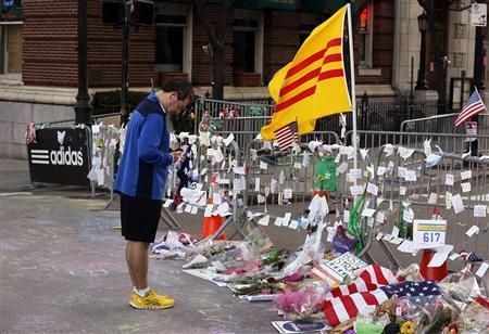 An early morning runner pauses to say a prayer at a memorial to the victims of the Boston Marathon bombings near the scene of the blasts on Boylston Street in Boston, Massachusetts April 21, 2013. REUTERS-Jim Bourg