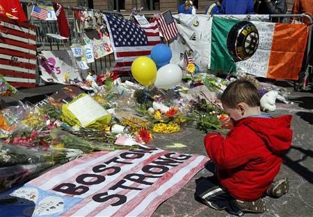 Two-year-old   Wesley Brillant of Natick,   Massachusetts kneels in front of a memorial to the victims of the Boston Marathon bombings near the scene of the blasts on Boylston Street in Boston, Massachusetts, April 21, 2013. REUTERS-Jim Bourg