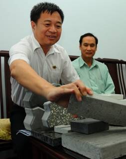Ông Trần Minh Chí (trái), chủ tịch HĐQT Công ty Thạch Anh, giới thiệu viên bêtông ốp tường làm bằng cát biển